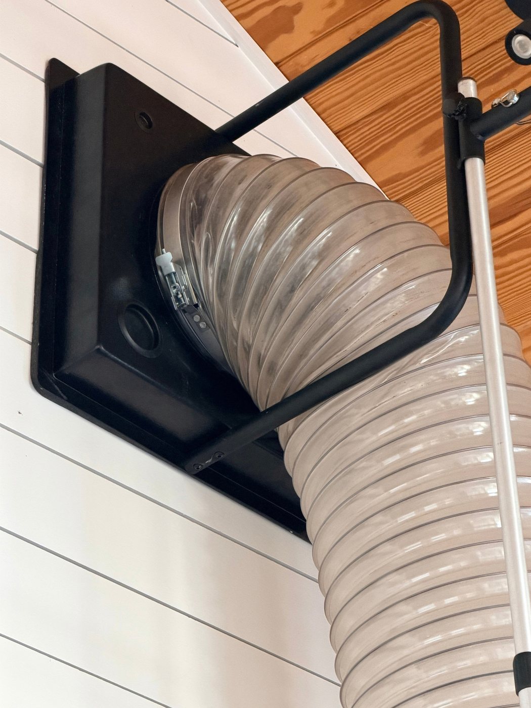 The negative-pressure collection hose sealed to a ceiling register during a duct cleaning